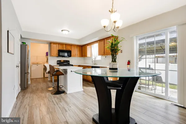 a kitchen with stainless steel appliances granite countertop a stove top oven a refrigerator a dining table and chairs with wooden floor