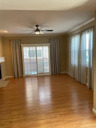 an empty room with wooden floor chandelier and windows
