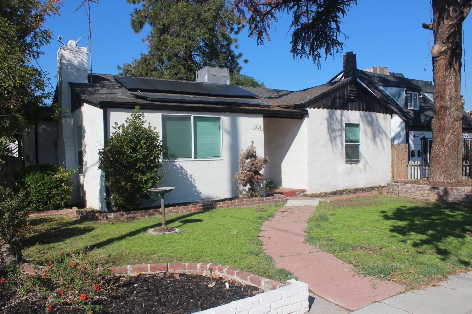a view of a house with a small yard plants and a large tree