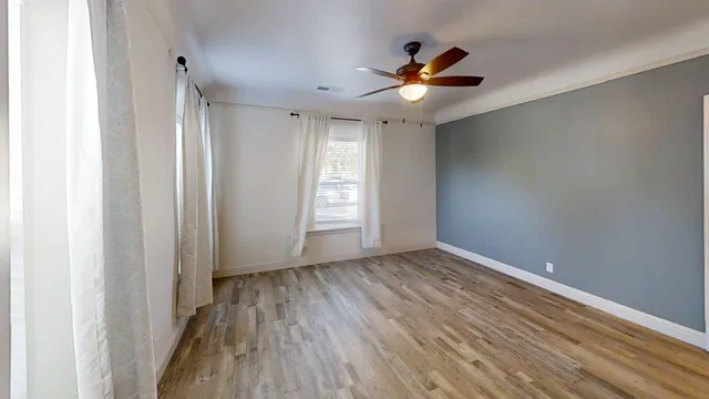 a view of empty room with wooden floor and fan