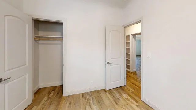 a view of an empty room with closet and wooden floor