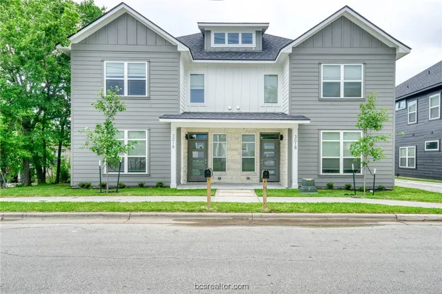 a front view of a house with a yard and trees