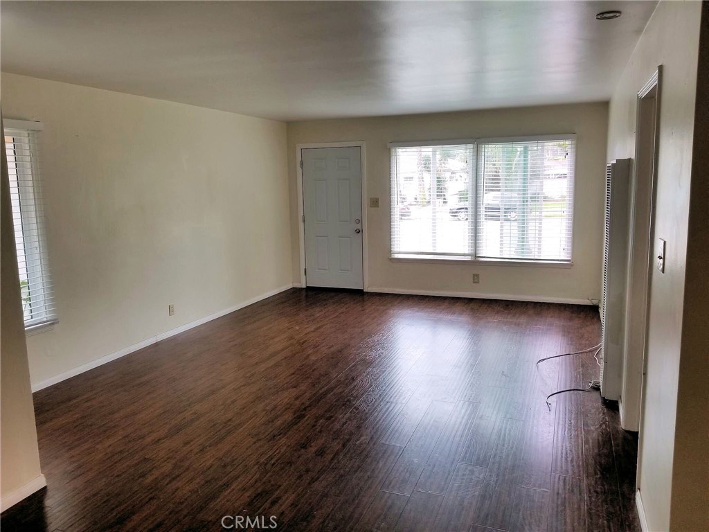 1405 South Broadway Santa Ana, CA 92707 - Photo 3 of 11 an empty room with wooden floor and windows with curtains