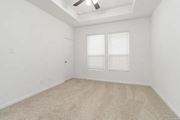 an empty room with chandelier fan and windows