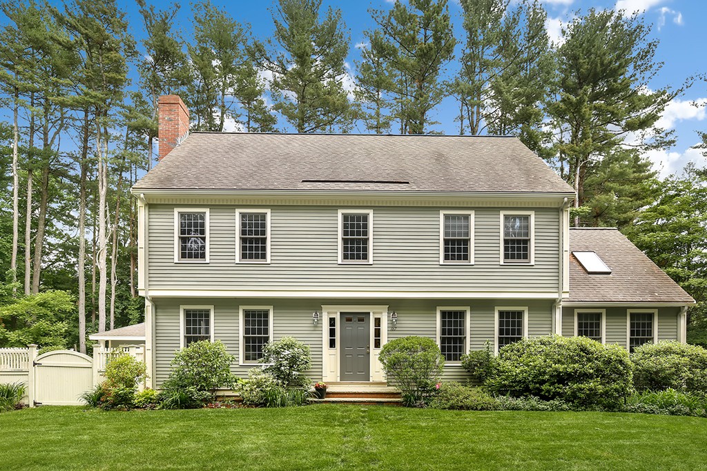 a view of a house with a yard plants and large tree