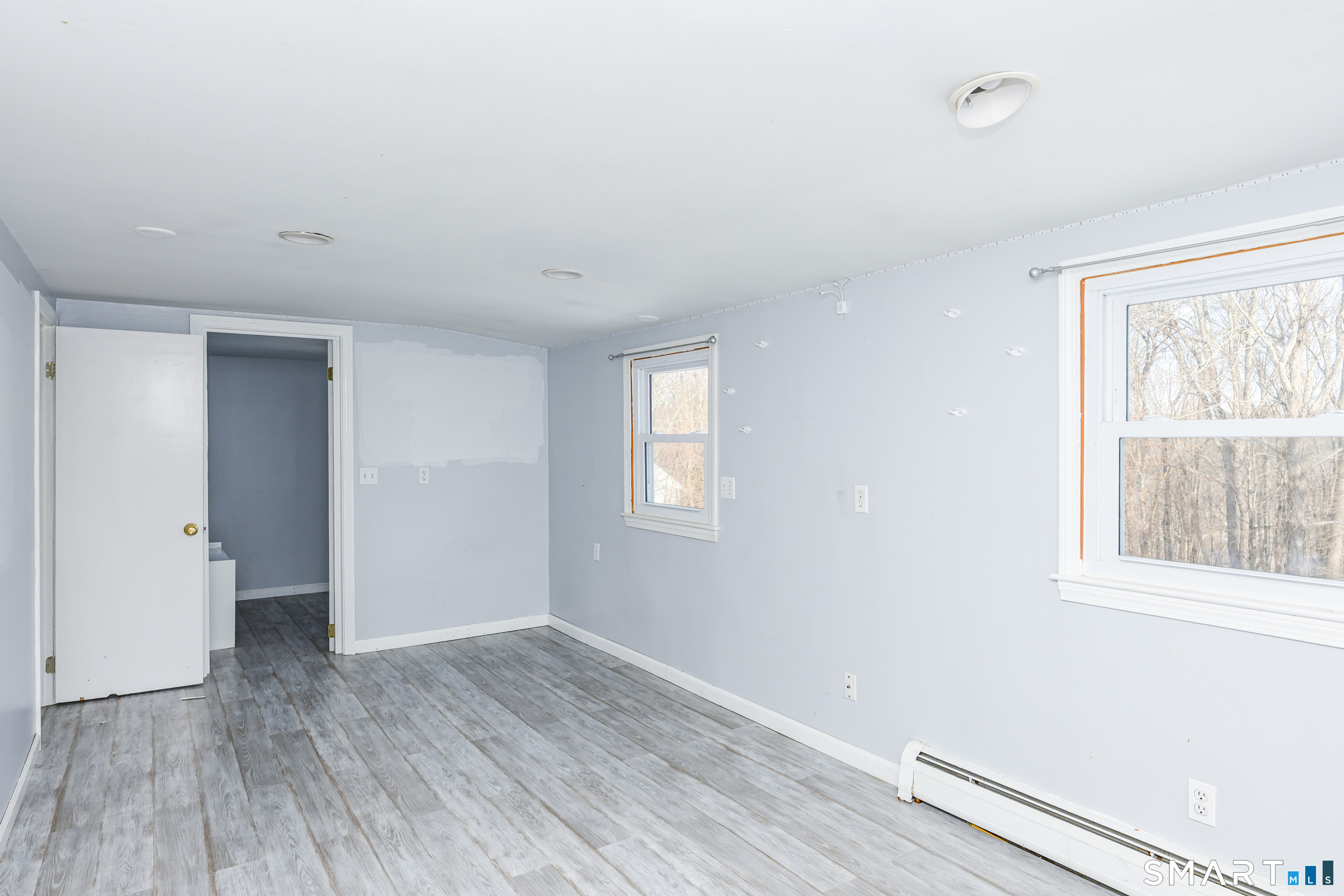 an empty room with wooden floor and windows