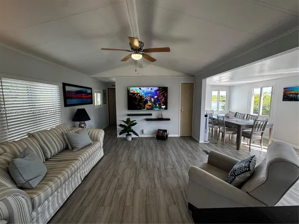 a living room with furniture a ceiling fan and a flat screen tv
