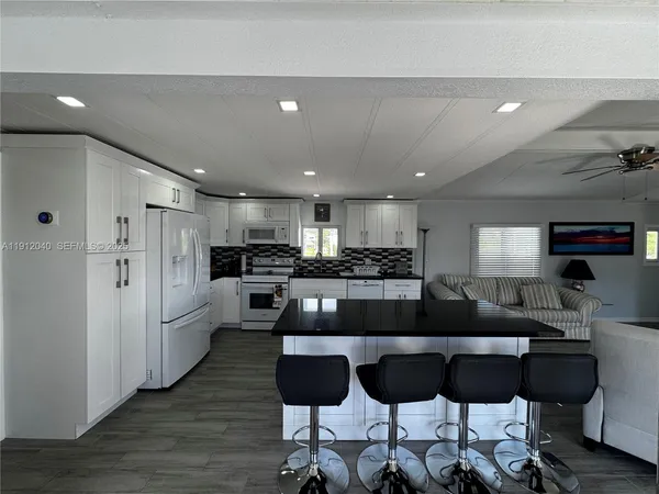 a large kitchen with stainless steel appliances kitchen island granite countertop a refrigerator a stove a sink a table and chairs