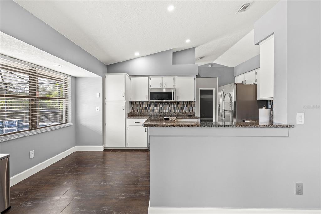 9508 Pine Terrace Court Windermere, FL 34786 - Photo 12 of 37 a kitchen with stainless steel appliances granite countertop a stove a sink a refrigerator white cabinets and a wooden floor