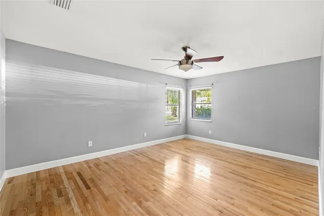a view of empty room with wooden floor and fan