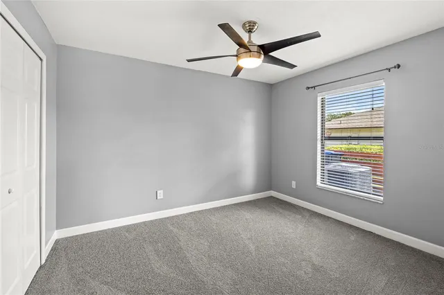 an empty room with a window and a fan