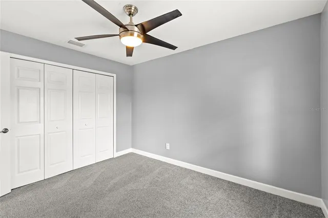 an empty room with a ceiling fan and a window