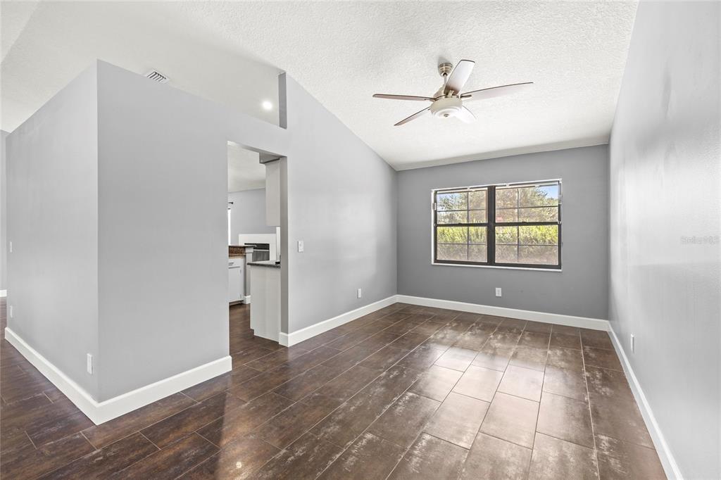 9508 Pine Terrace Court Windermere, FL 34786 - Photo 8 of 37 an empty room with wooden floor chandelier fan and windows