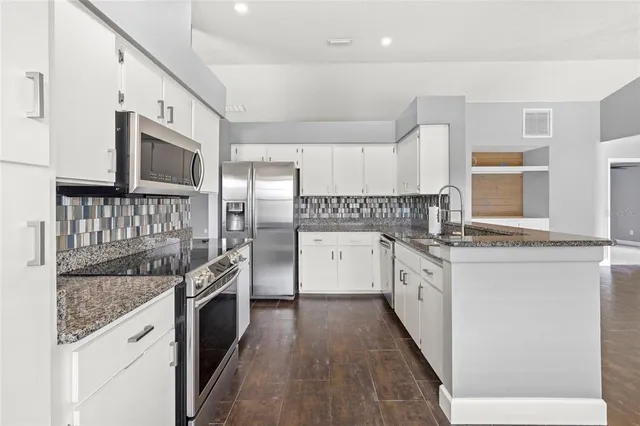 a kitchen with stainless steel appliances granite countertop a stove a sink and a refrigerator