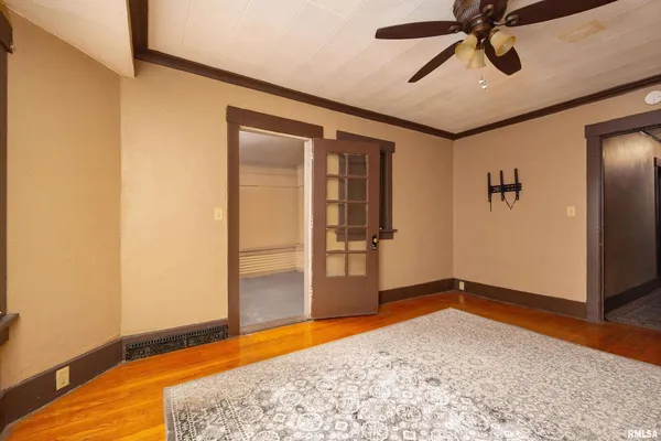 an empty room with wooden floor closet and windows
