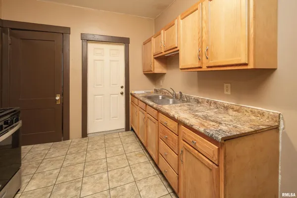 a kitchen with granite countertop a sink stove and cabinets
