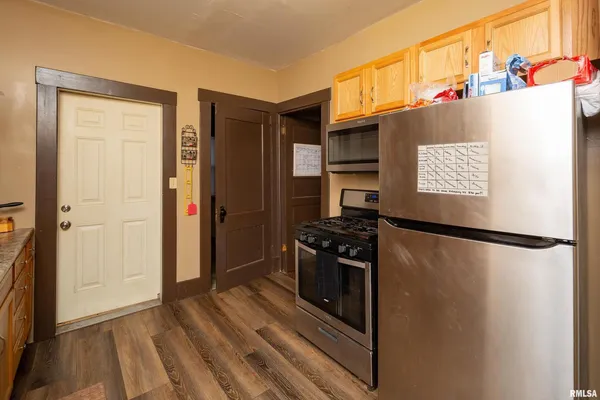 a view of a refrigerator in kitchen and an empty room