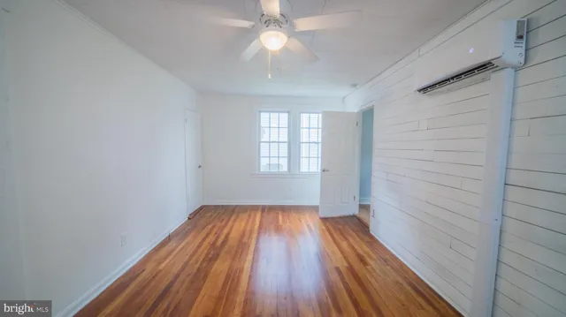 a view of empty room with wooden floor and fan