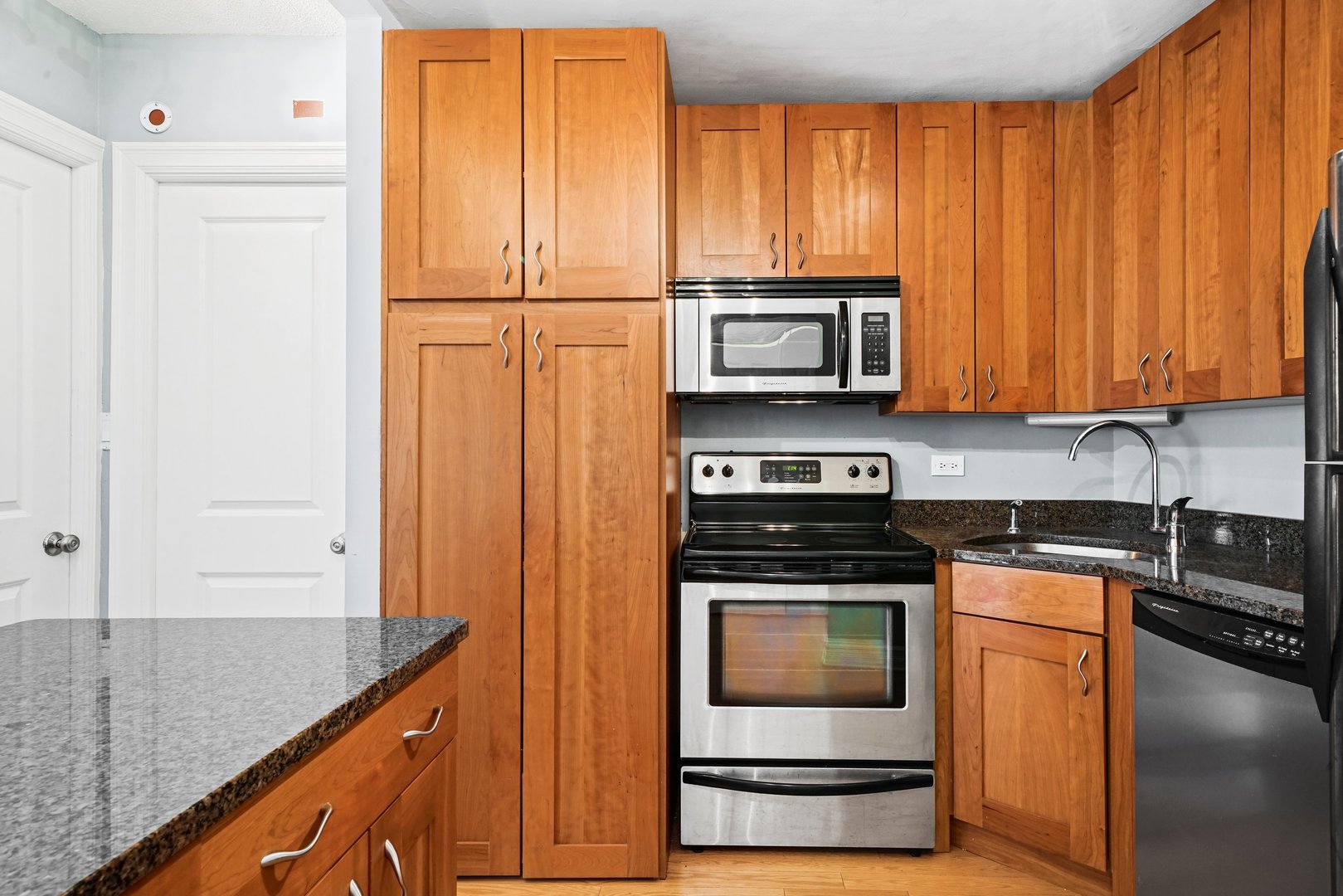 2930 North Sheridan Road, Unit 805 Chicago, IL 60657 - Photo 9 of 21 a kitchen with granite countertop wooden cabinets and stainless steel appliances