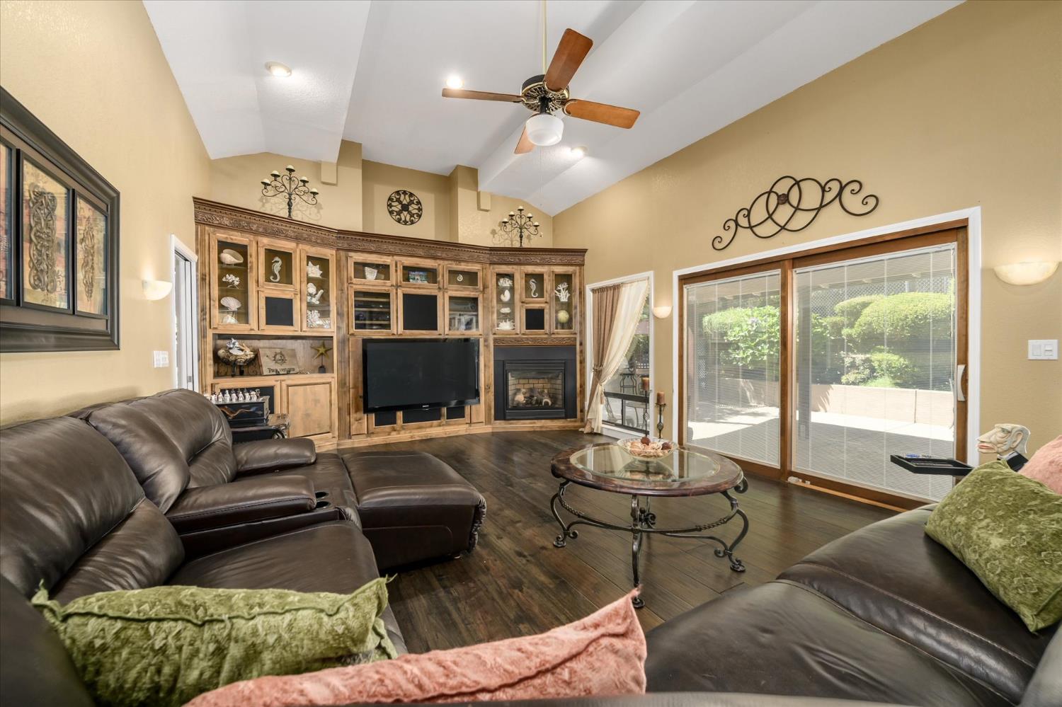 3165 Oakwood Road Cameron Park, CA 95682 - Photo 10 of 55 The formal living room features engineered hickory, scraped flooring and soaring cathedral ceilings that create an open, airy feel. Beautifully crafted built-in cabinetry surrounds the fireplace, adding warmth and character, while a large glass slider extends the living space outdoors, inviting natural light and seamless access to the exterior.