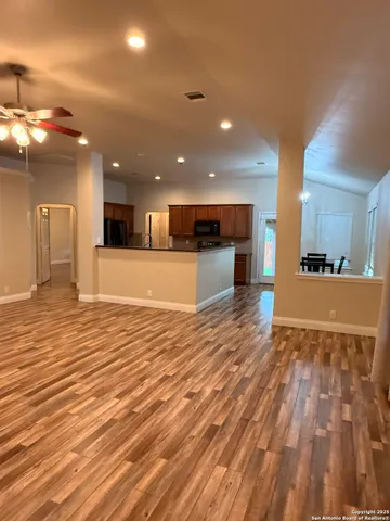 a view of a big room with wooden floor and a kitchen