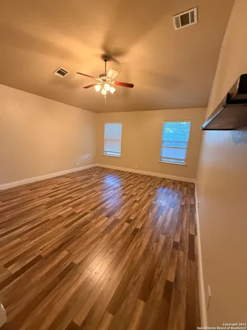 a view of an empty room with wooden floor and a window