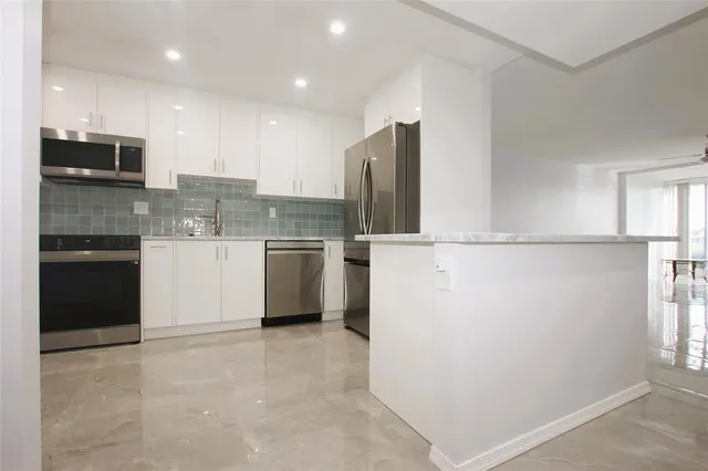 a kitchen with stainless steel appliances granite countertop a refrigerator a stove and a sink