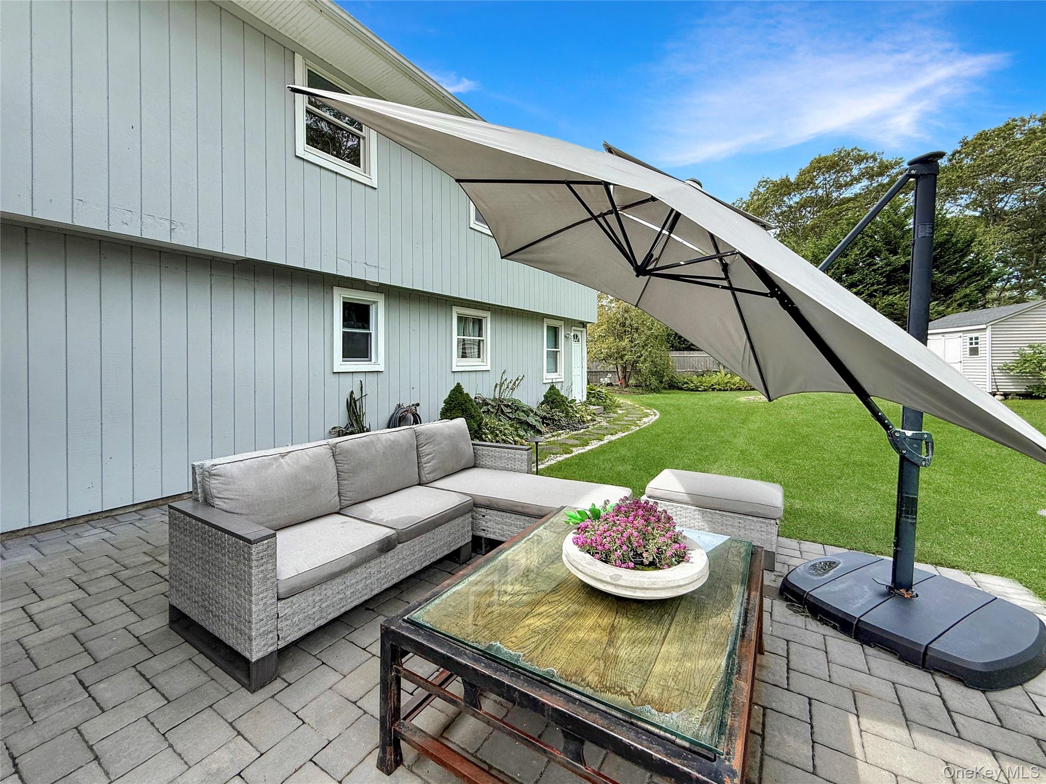 8 Westerly Court Hampton Bays, NY 11946 - Photo 5 of 26 a view of a patio with couches table and chairs under an umbrella