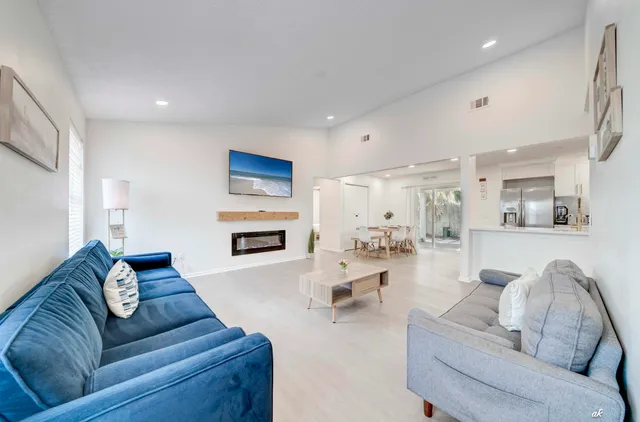 a kitchen with stainless steel appliances kitchen island granite countertop a stove a sink a refrigerator and white cabinets with wooden floor