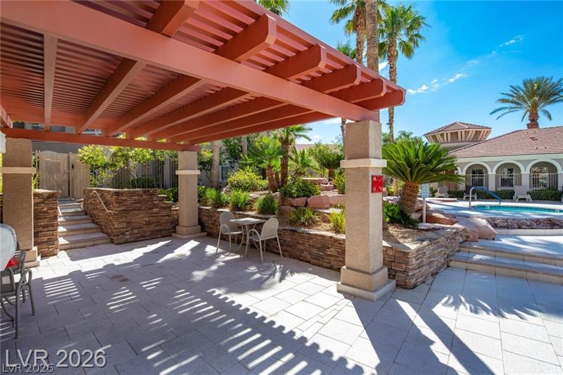 10550 West Alexander Road, Unit 2148 Las Vegas, NV 89129 - Photo 24 of 41 A tranquil outdoor retreat with a shaded patio, vibrant landscaping, and nearby swimming pool.