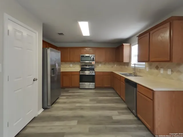 a large kitchen with wooden floor and stainless steel appliances