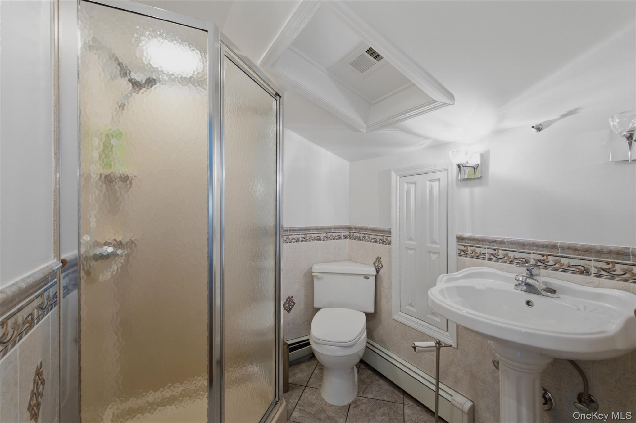 12 Leeside Road Carmel, NY 10512 - Photo 26 of 44 Full Bathroom in 3rd bedroom on the second level featuring a glass-enclosed shower, pedestal sink, ceramic tile flooring, and decorative wainscoting