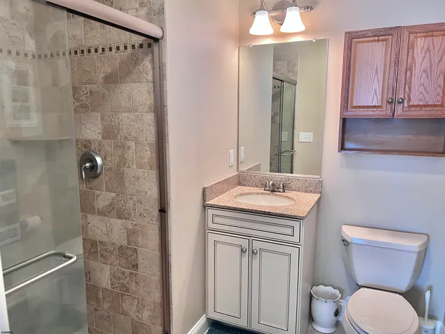 a bathroom with a granite countertop toilet a sink and a mirror