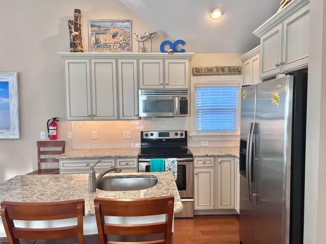 a kitchen with stainless steel appliances granite countertop a refrigerator a stove and a sink with wooden floor