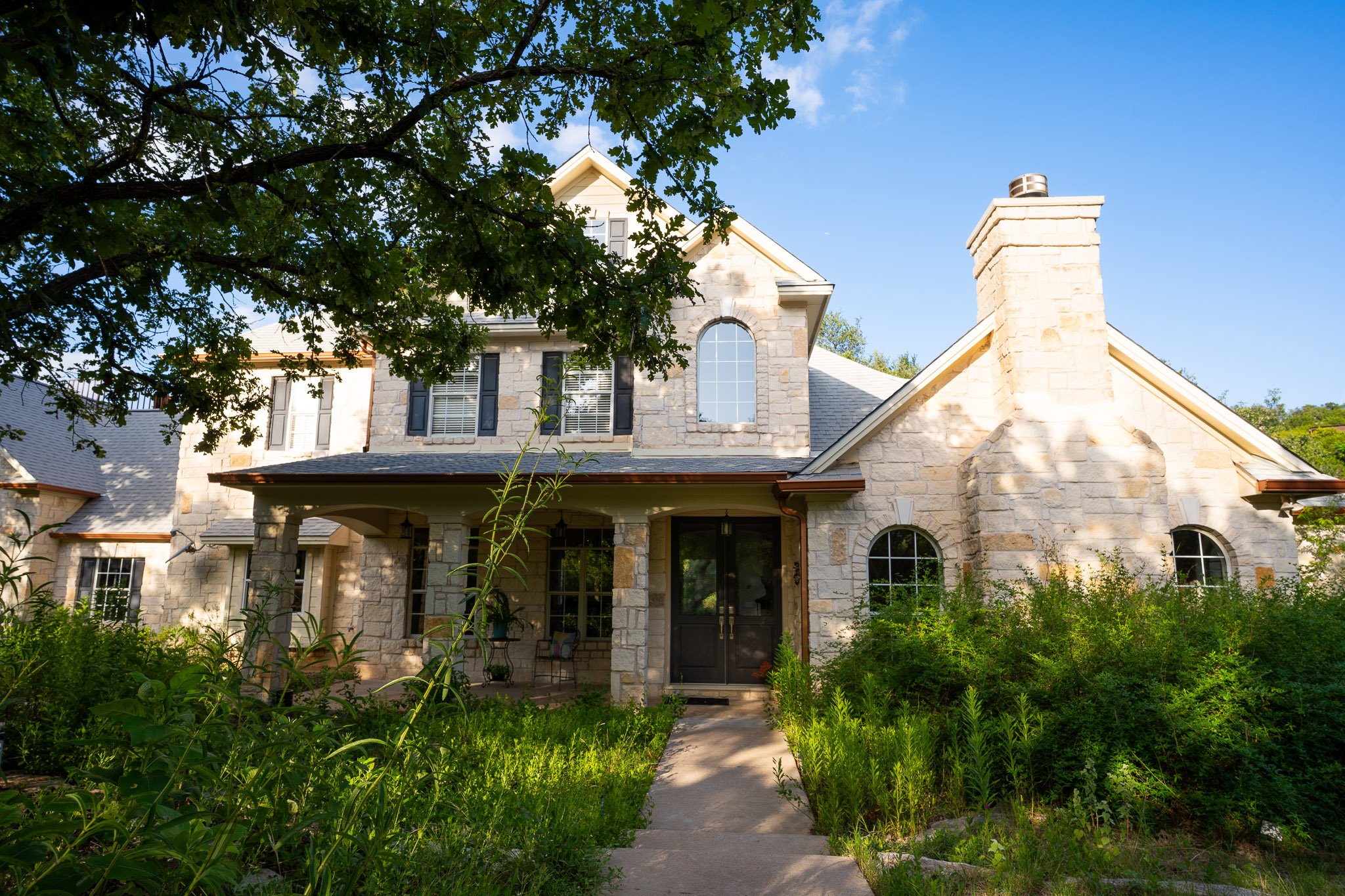 13800 Lone Rider Trail Austin, TX 78738 - Photo 3 of 32 A stone-clad residence with arched windows and a covered front porch awaits your arrival.