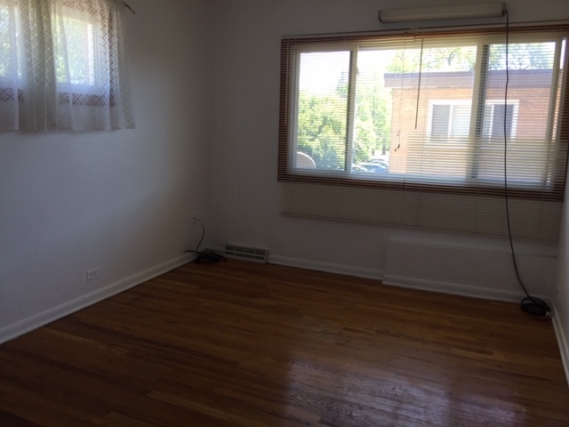 10071 Frontage Road, Unit G Skokie, IL 60077 - Photo 5 of 22 a view of an empty room with wooden floor and a window