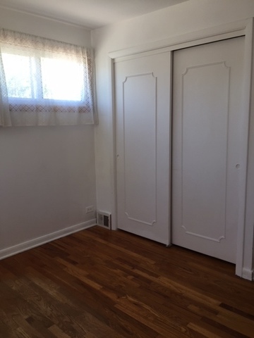 10071 Frontage Road, Unit G Skokie, IL 60077 - Photo 8 of 22 an empty room with wooden floor and windows with curtains