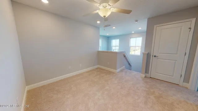 an empty room with chandelier fan and windows