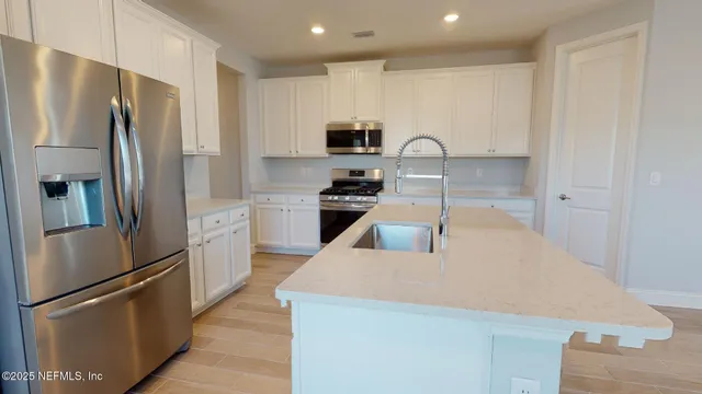a kitchen with stainless steel appliances granite countertop a refrigerator a stove and a sink with wooden floor