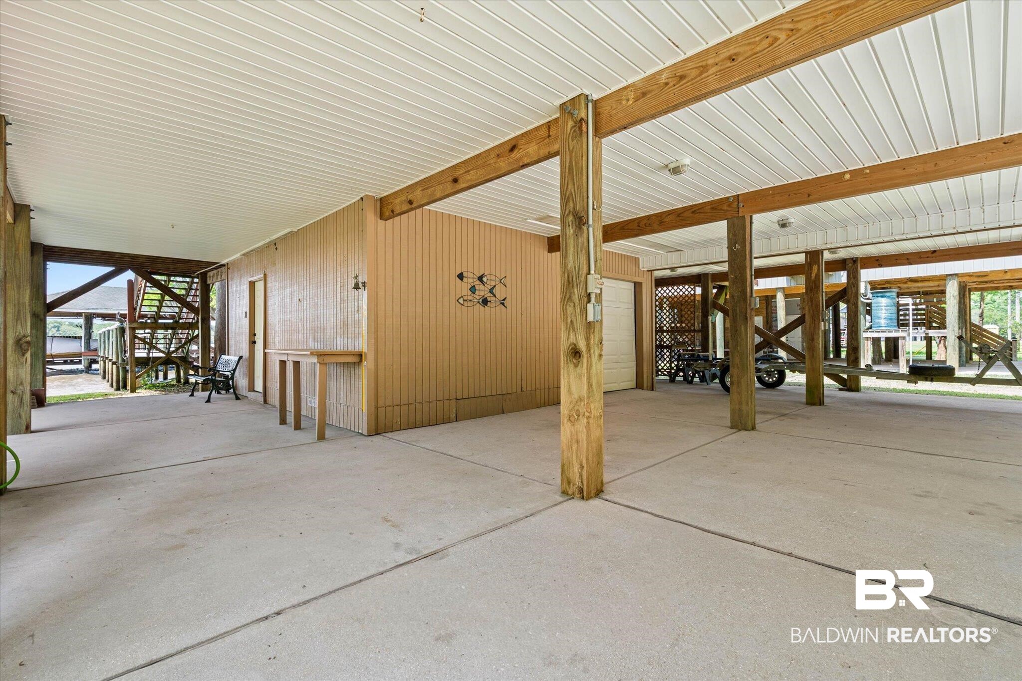 41923 Bayou Road Bay Minette, AL 36507 - Photo 25 of 35 Spacious covered concrete pad featuring exposed wood structural beams, a wood-paneled ceiling, and a built-in storage area with a roll-up door