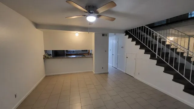 a view of an empty room with stairs and a ceiling fan