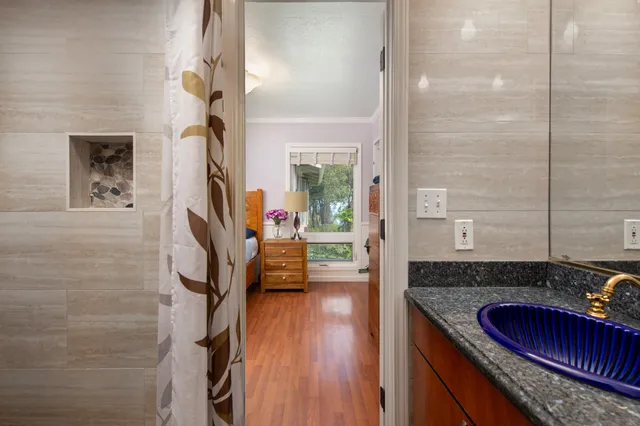 a bedroom with a bed mirror and painting on the wall