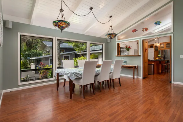 a dining room with wooden floor a chandelier a wooden table and chairs