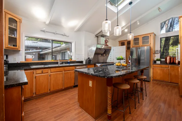 a kitchen with stainless steel appliances granite countertop a stove and a wooden floors