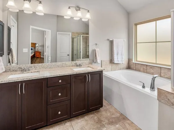 a spacious bathroom with a tub sink and mirror