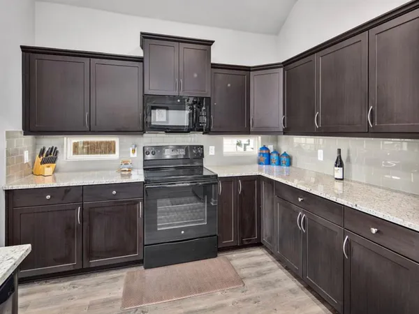 a kitchen with stainless steel appliances granite countertop a sink a stove and cabinets
