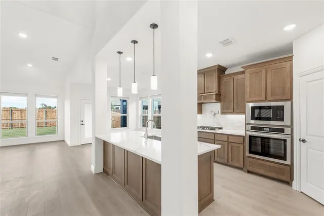 a kitchen with kitchen island granite countertop a refrigerator a sink and cabinets