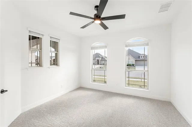 an empty room with windows and fan