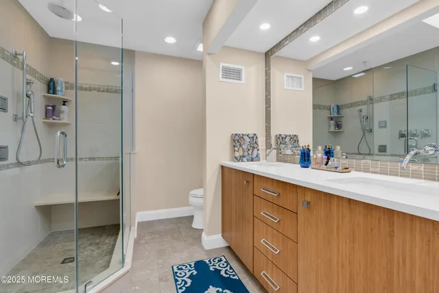 a spacious bathroom with a double vanity sink a mirror and a shower