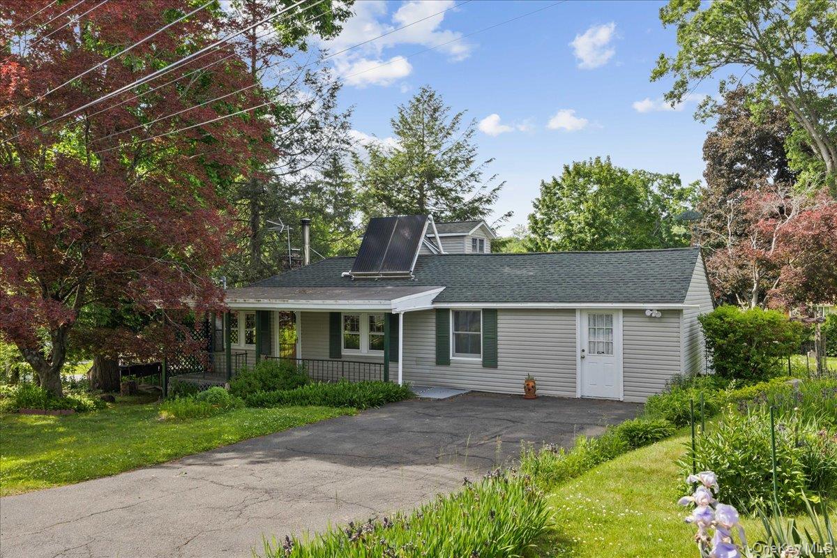 Ranch-style residence featuring light gray siding, a dark green shingle roof, and a solar panel installation